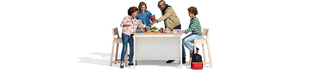 A family of four has fun multi-tasking at the kitchen table.